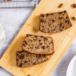Slices of bran loaf filled with fruit on a cutting board,