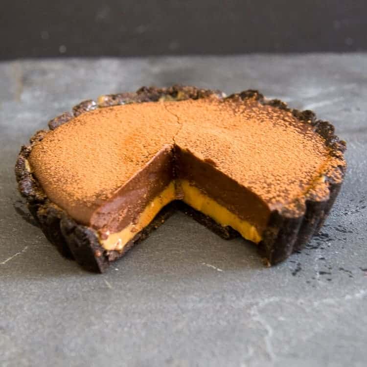 Chocolate caramel oreo tart with a slice taken out of it