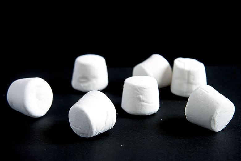 White marshmallows scattered on a black background