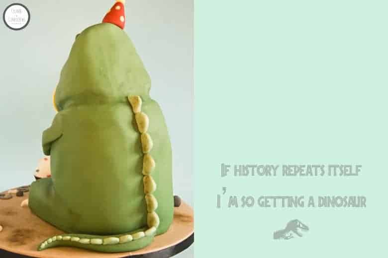Cute green T-Rex dinosaur cake wearing a red party hat