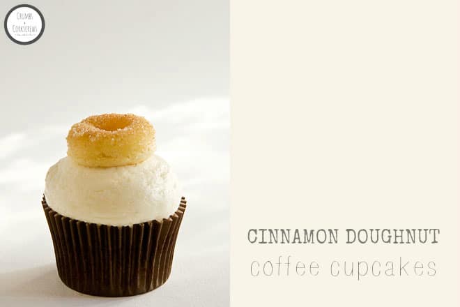 A cupcake in a brown wrapper with smooth cream cheese frosting, and a sugar mini doughnut on top.