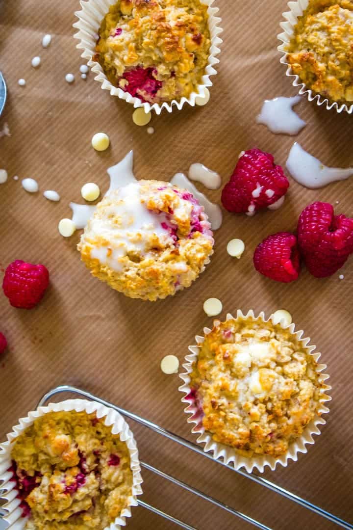 Golden muffins with raspberries drizzled with white icing on top.