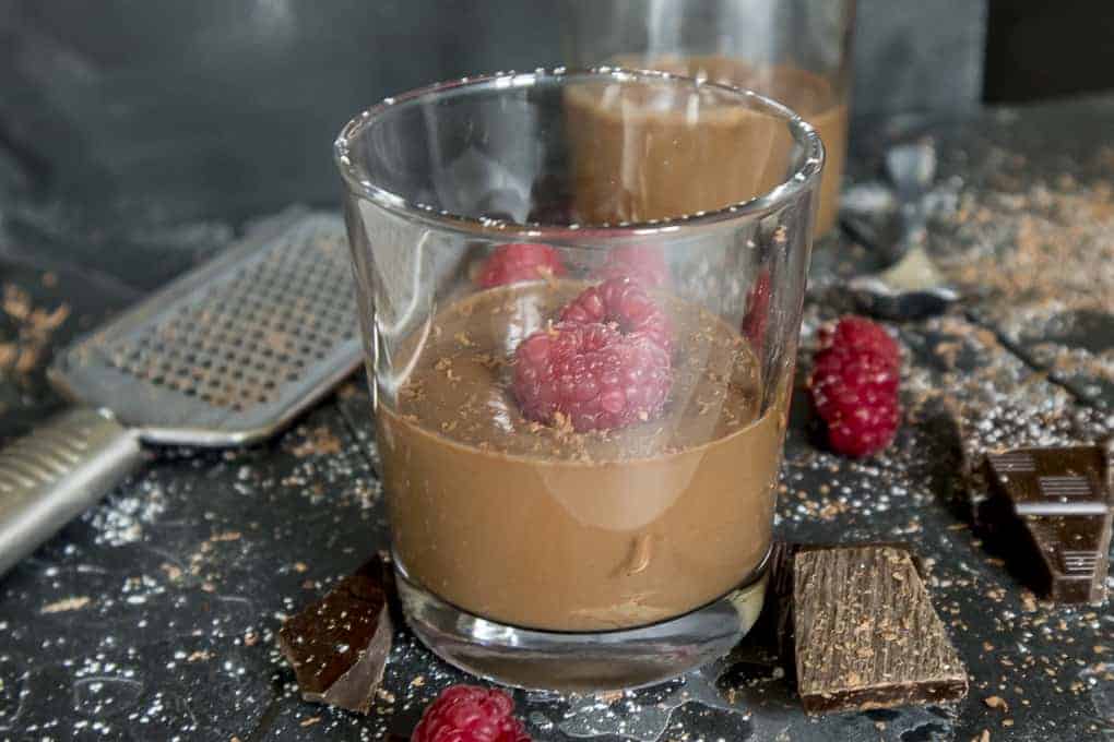 Chocolate pudding in a glass with fresh raspberries and dark chocolate
