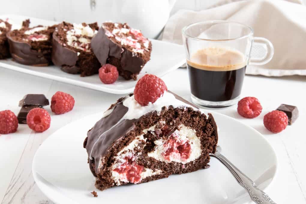 Fluffy, light and delicious raspberry chocolate roll, filled with whipped cream and fresh berries, covered in ganache