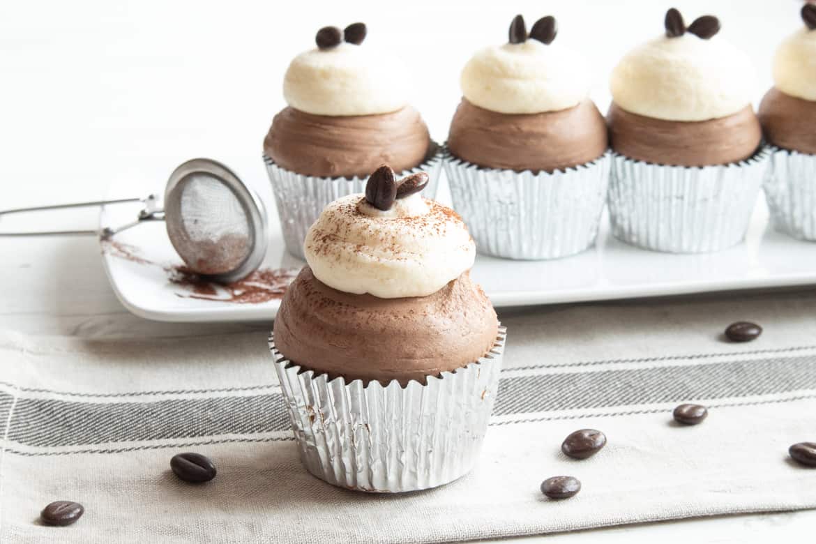 Chocolate cupcakes lined up with chocolate and cream cheese frosting