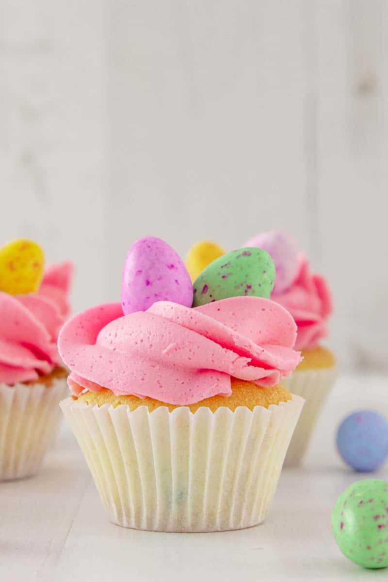 Delight your friends and family for Easter with these cute and delicious mini egg cupcakes. Soft white chocolate cake speckled with coloured candy drops, and topped with a fluffy white chocolate buttercream frosting and the best Easter candy ever... mini eggs.