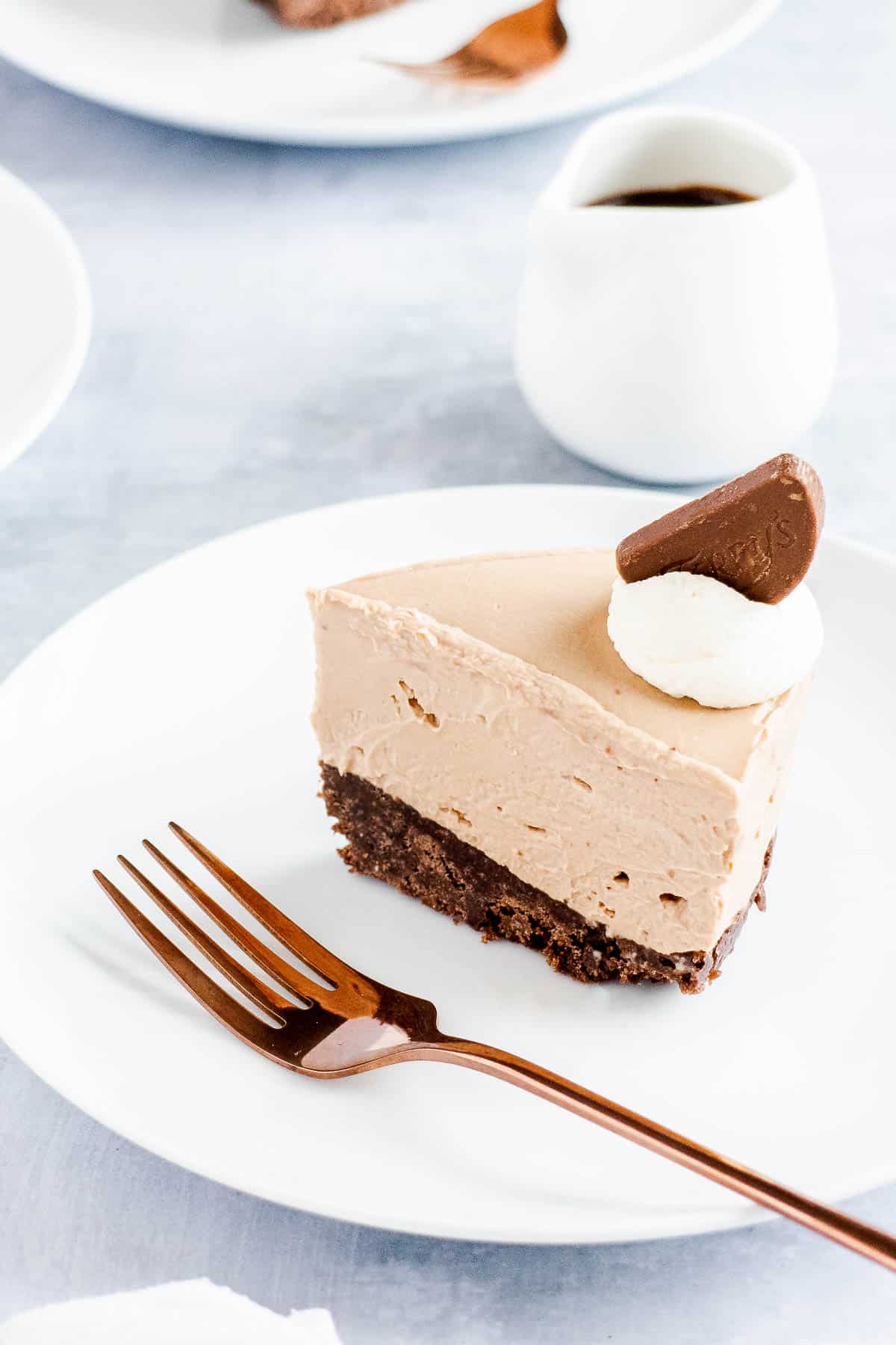 Slice of chocolate cheesecake on a white plate with a fork next to it