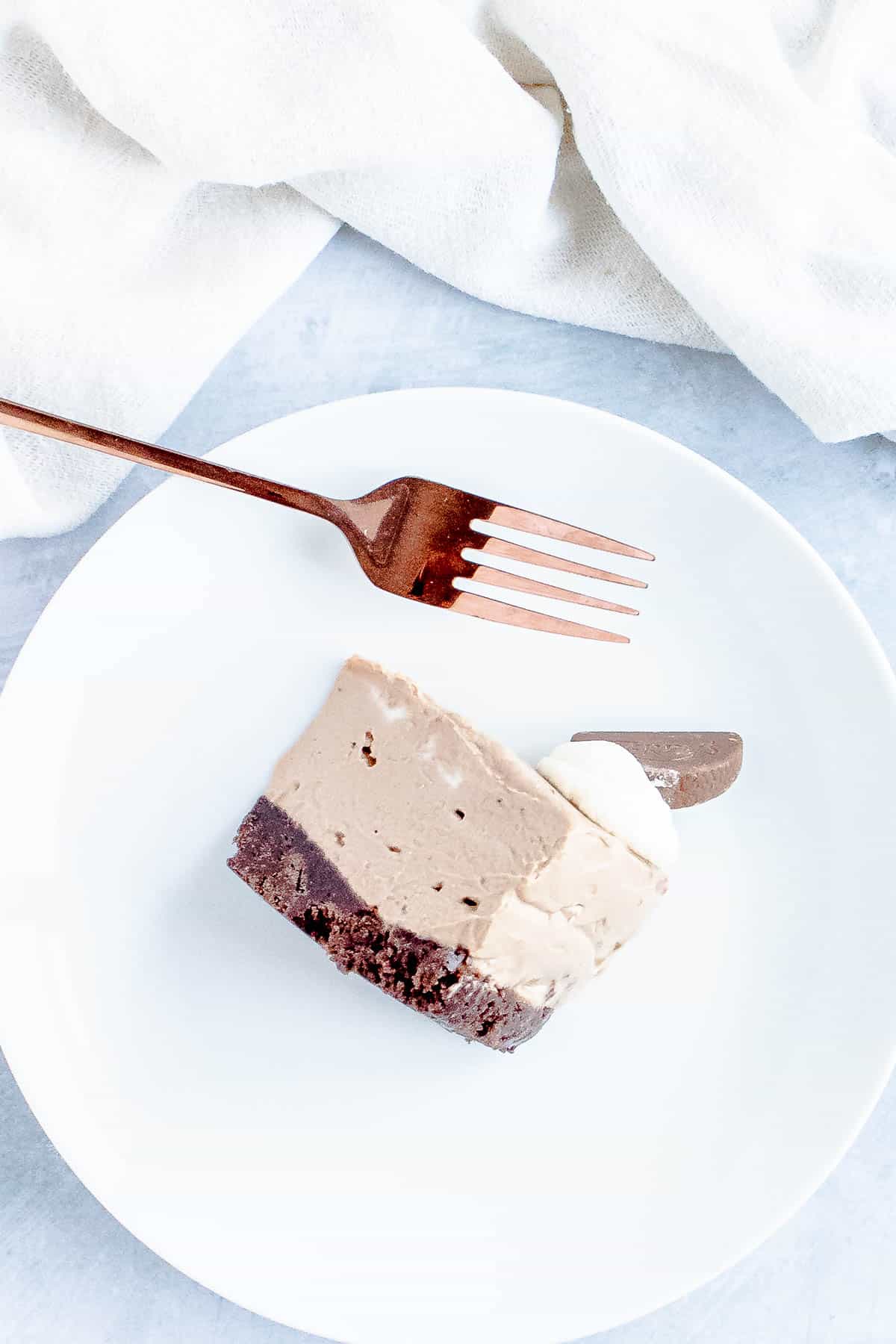 Slice of no-bake chocolate cheesecake on a white plate with a fork next to it