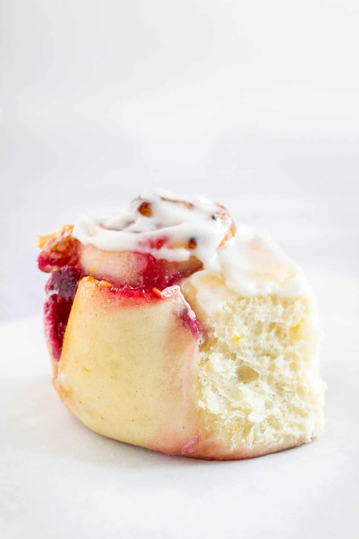Close up of lemon raspberry swirl roll filled with raspberry jam and iced with white glaze icing