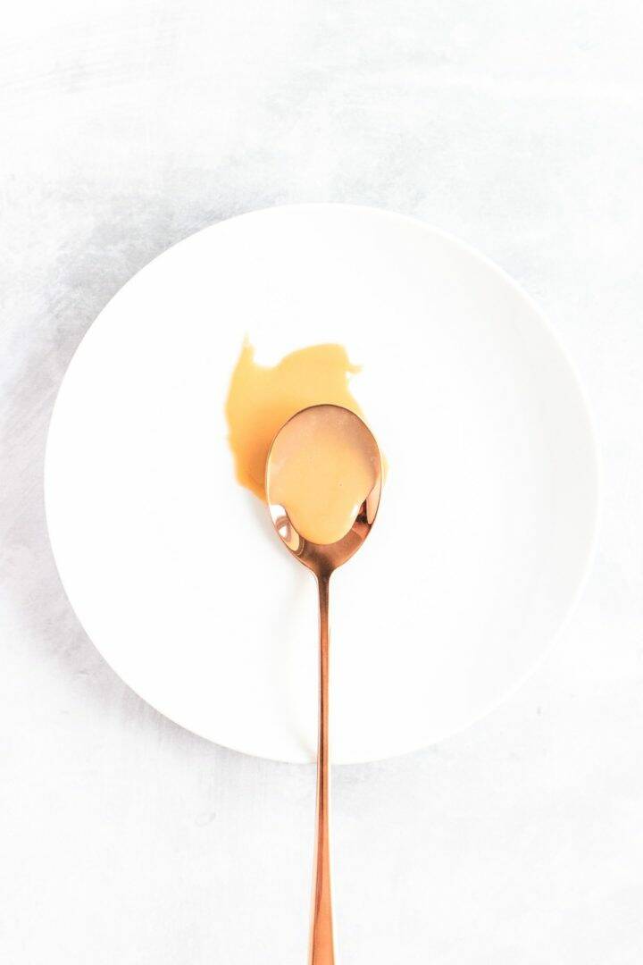White plate with a spoon in the centre that has been dipped in easy salted caramel sauce