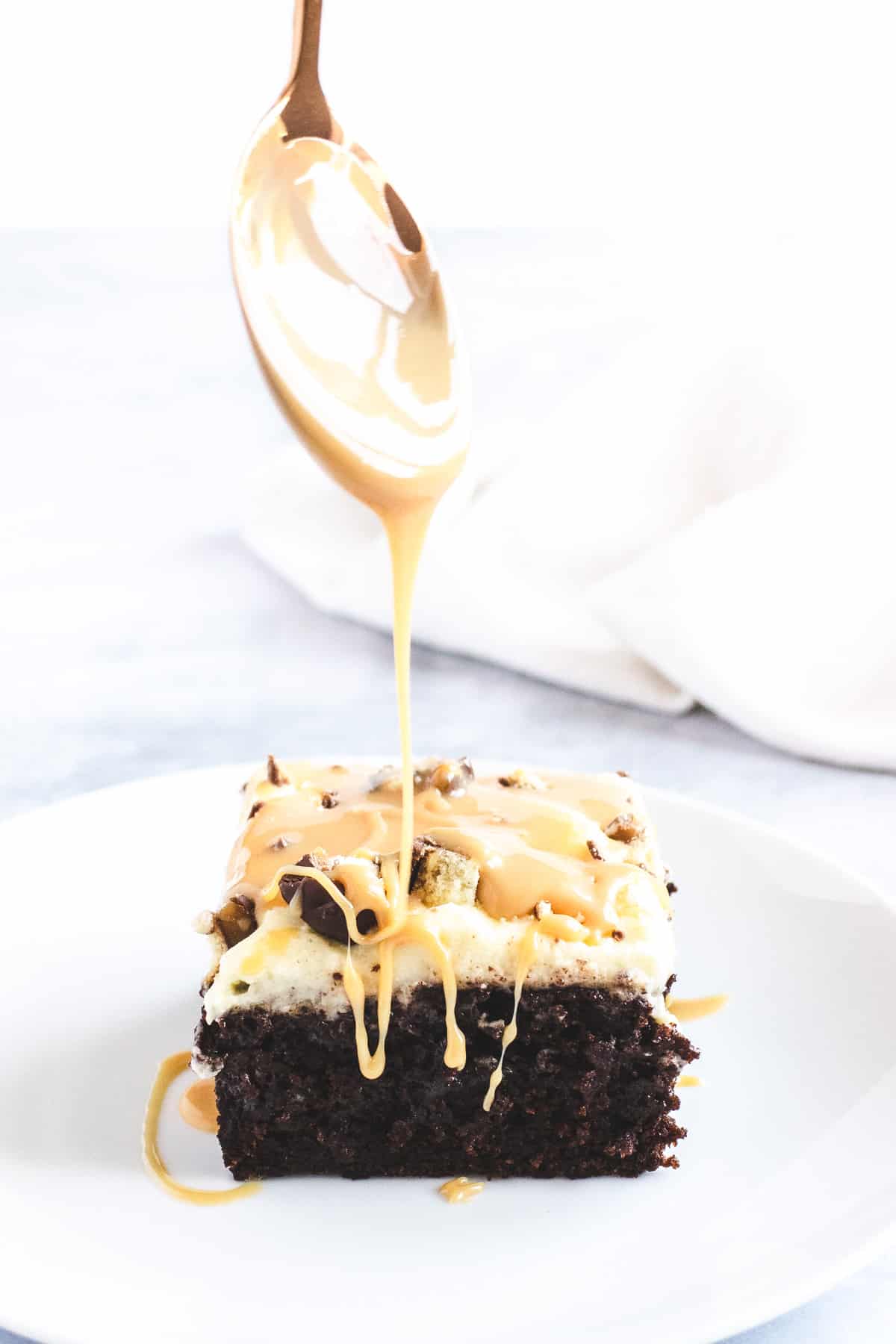 Slice of chocolate cake being drizzled in caramel sauce