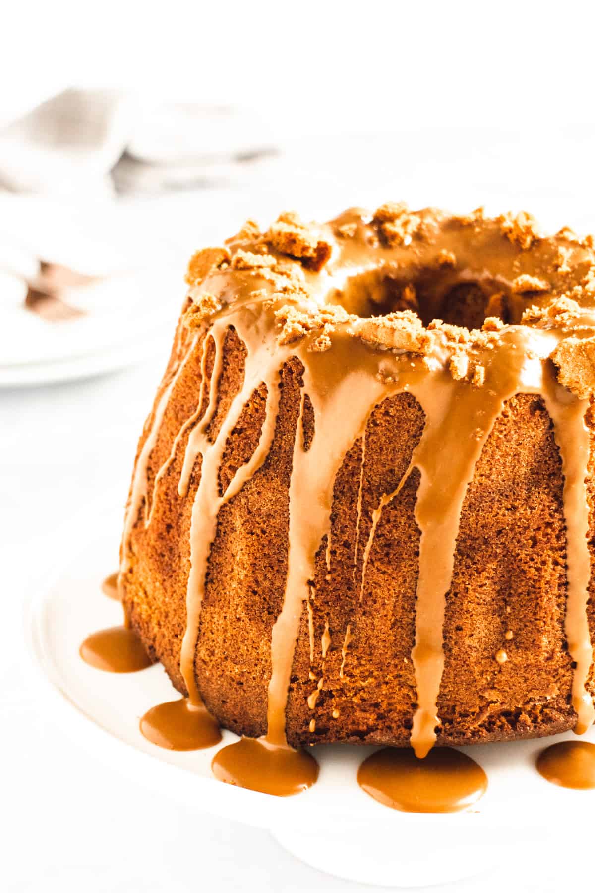 Biscoff Bundt cake on a white cake stand drizzled with a Biscoff cookie glaze