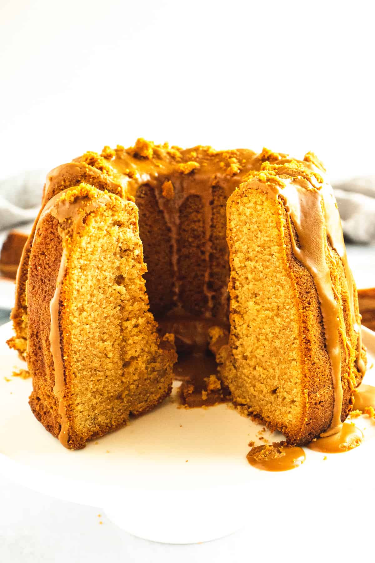 Circular cake drizzled with caramel Biscoff glaze with a slice cut out