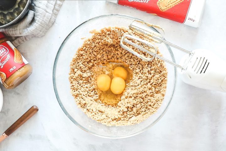 Three eggs in a large mixing bowl with cake dry ingredients