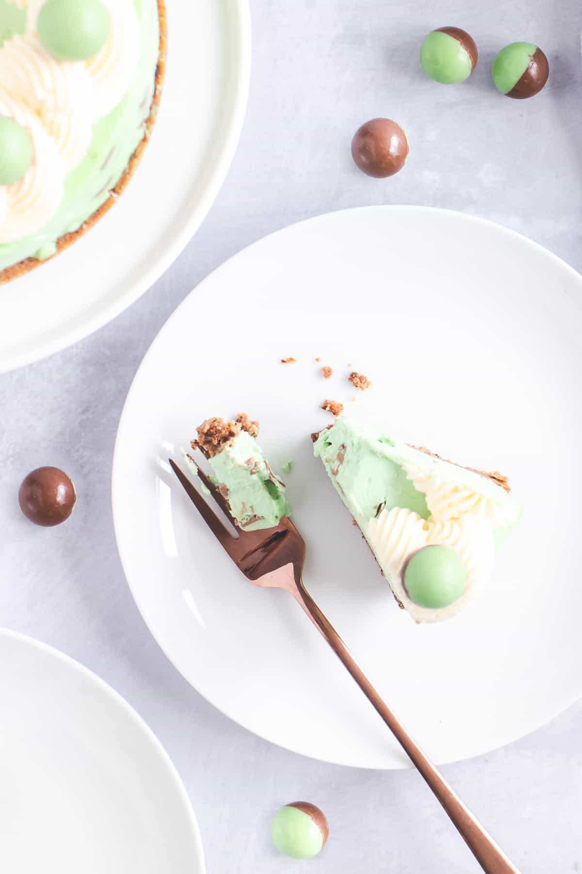 Slice of mint cheesecake on a plate with a fork next to it