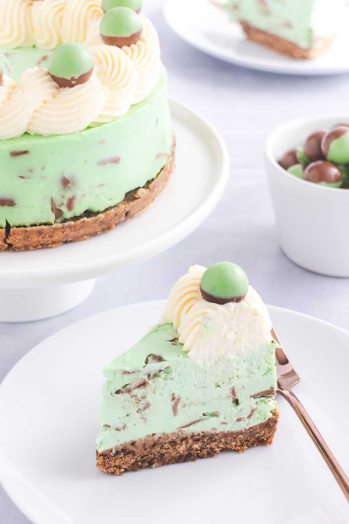 Mint green cheesecake with chunks of chocolate in the filling and topped with Mint Aero bubbles