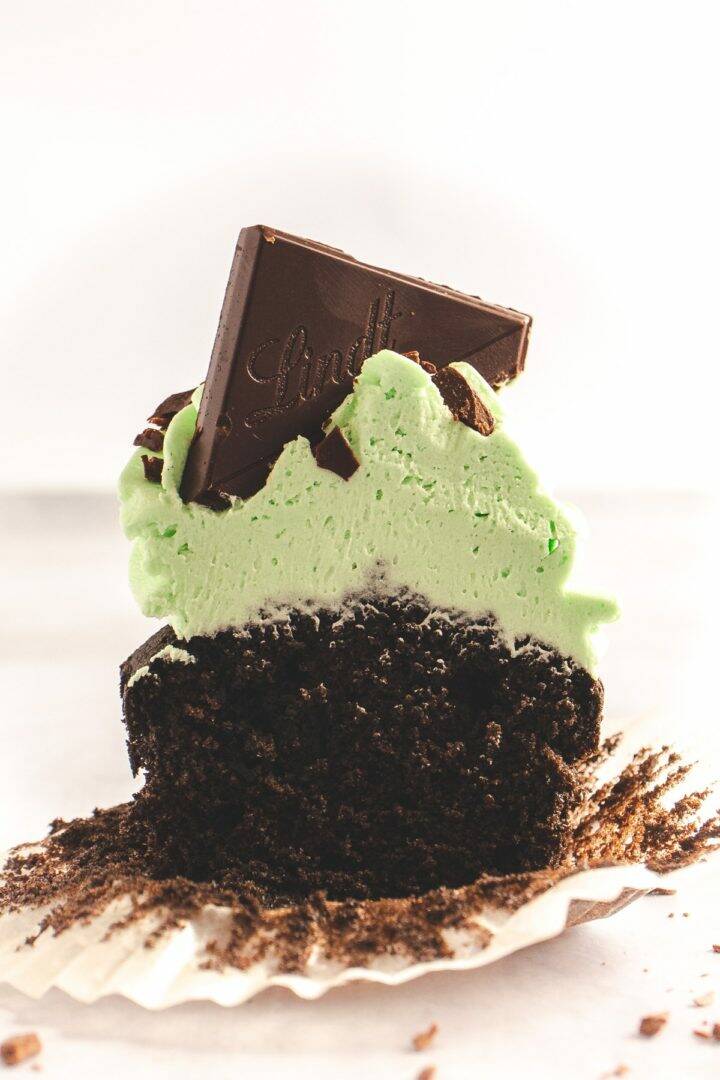 Half of a chocolate cupcake with green frosting on top