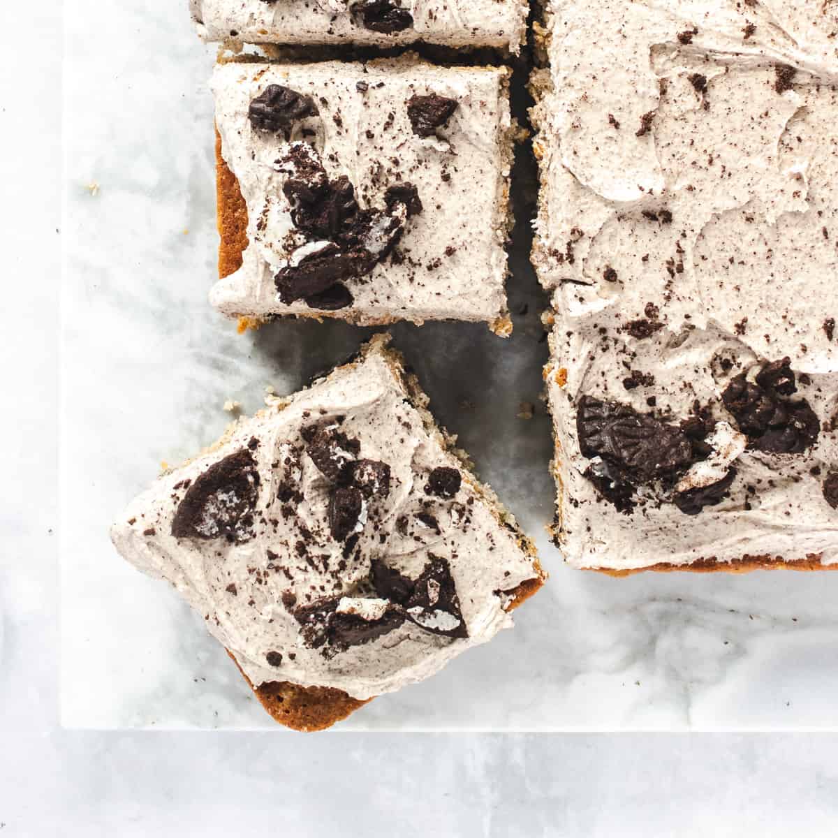 Oreo sheet cake on a marble pastry board cut into square pieces