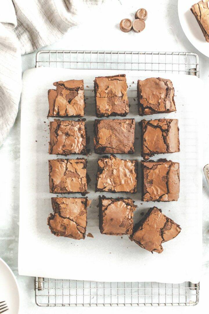 Brownies cut into square on a wire cooling rack with a spatula and chocolates nearby