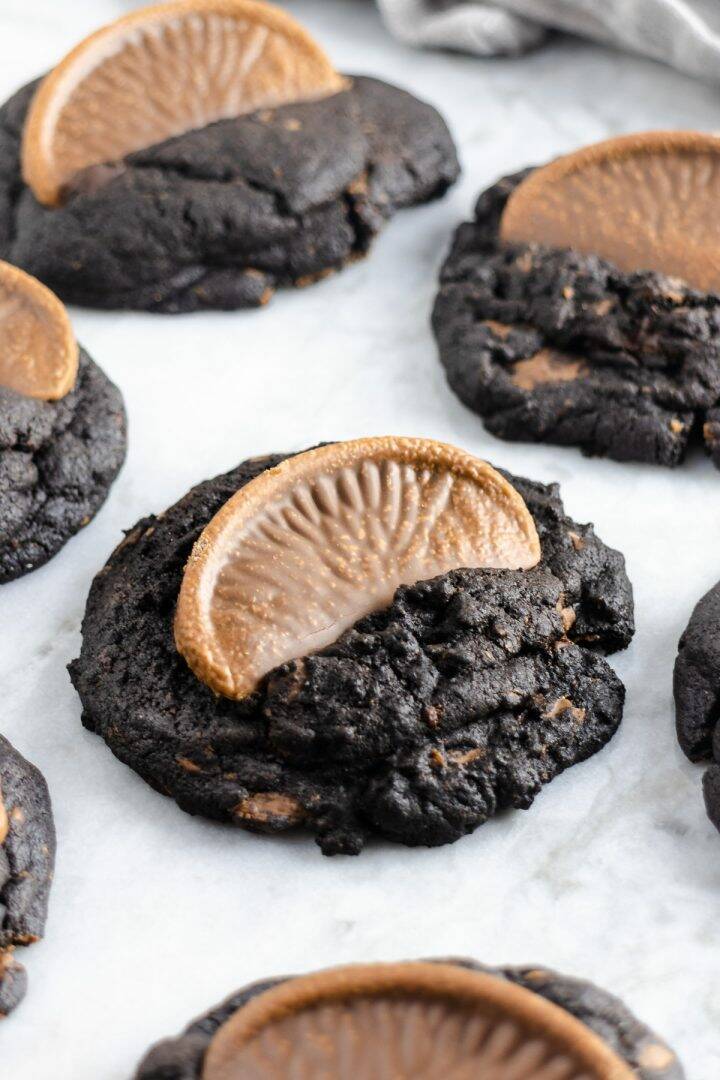 Dark chocolate cookies lined up on baking parchment