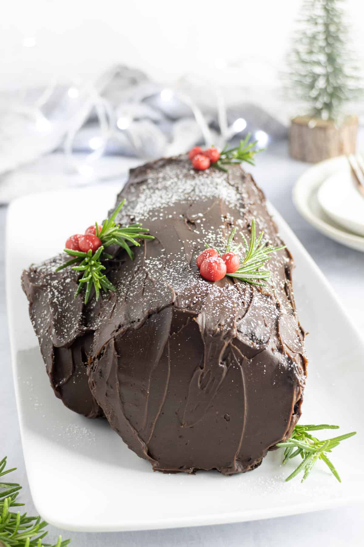 Chocolate roulade decorated with chocolate icing and icing sugar and sugar berries and holly sprigs
