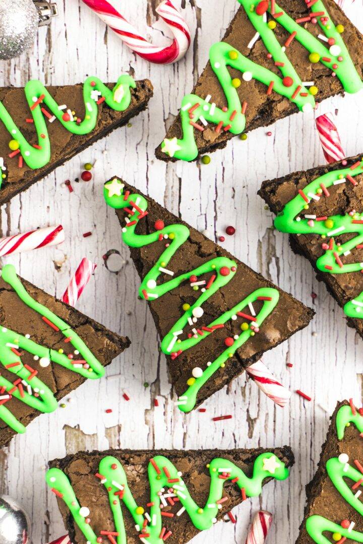 Brownies cut into triangles decorated with green icing, sprinkles and candy canes