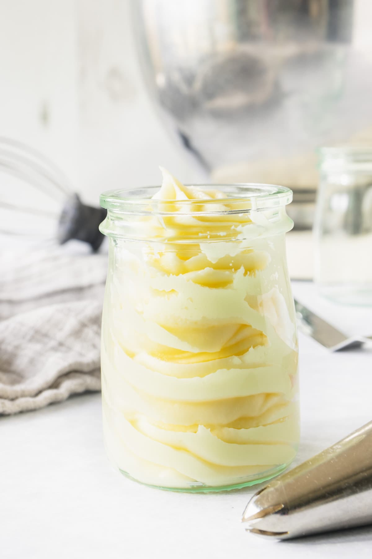 Glass jar full of swirls of pale cream frosting