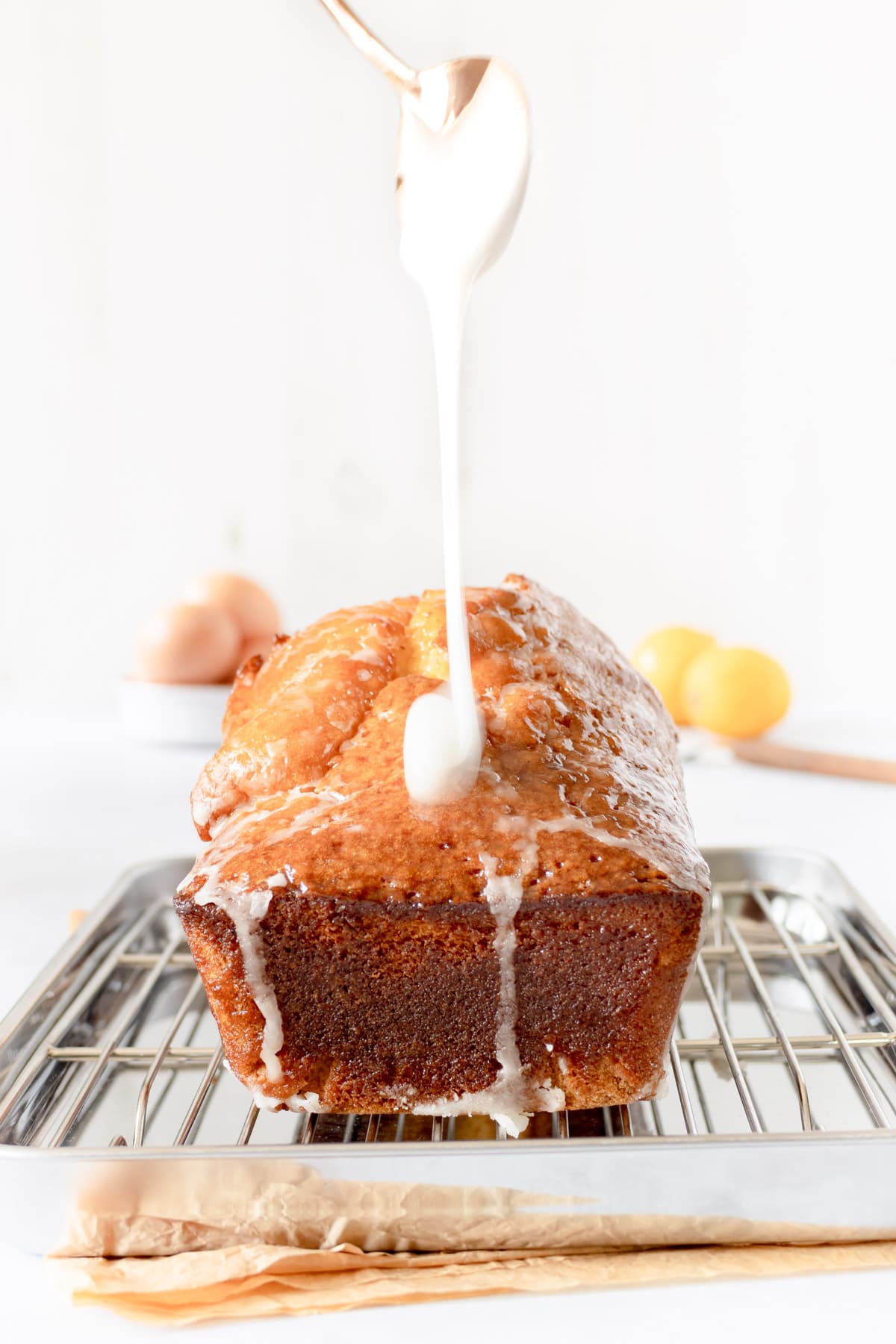 Drizzling icing over a lemon loaf with a spoon