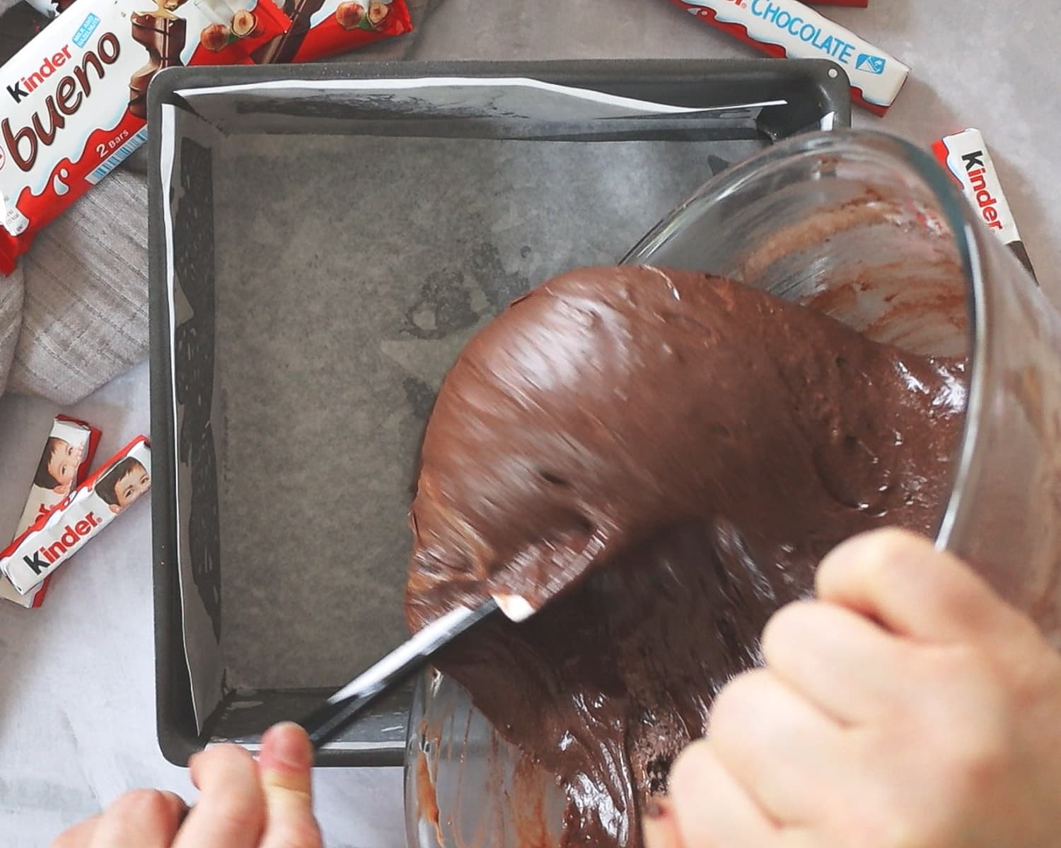 Pouring brownie batter into a lined baking pan