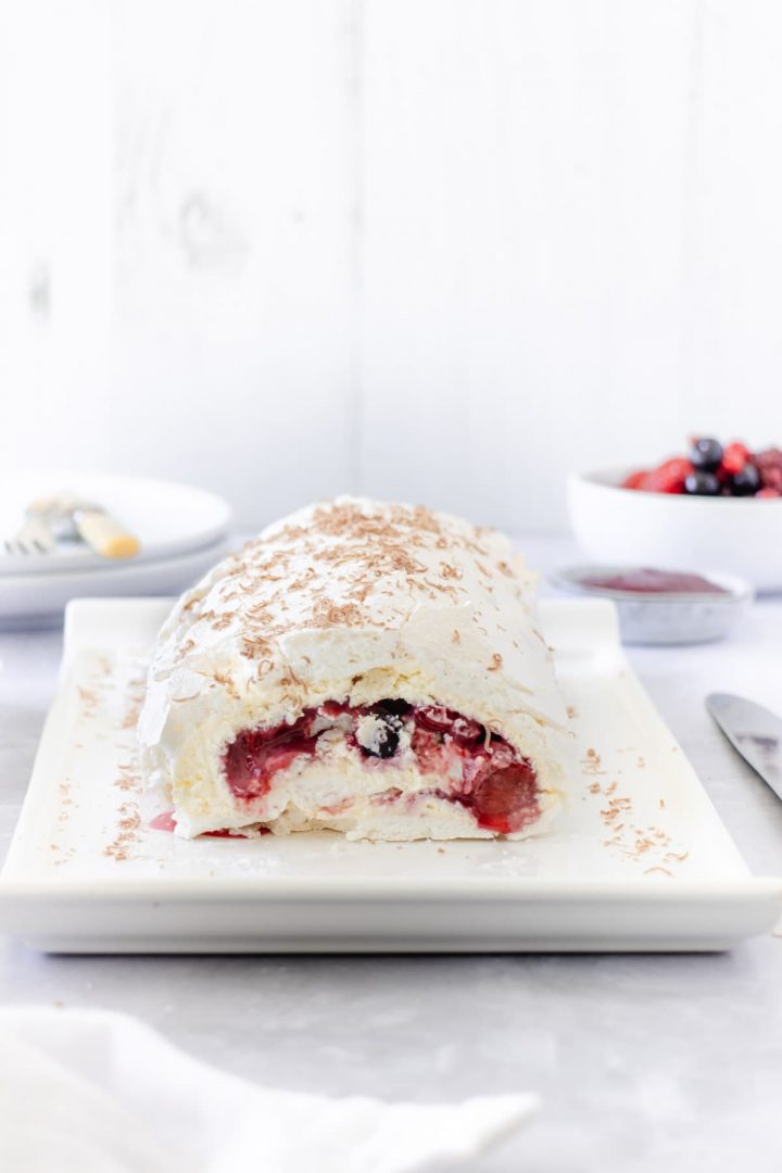 Red berries inside a meringue roll with whipped cream