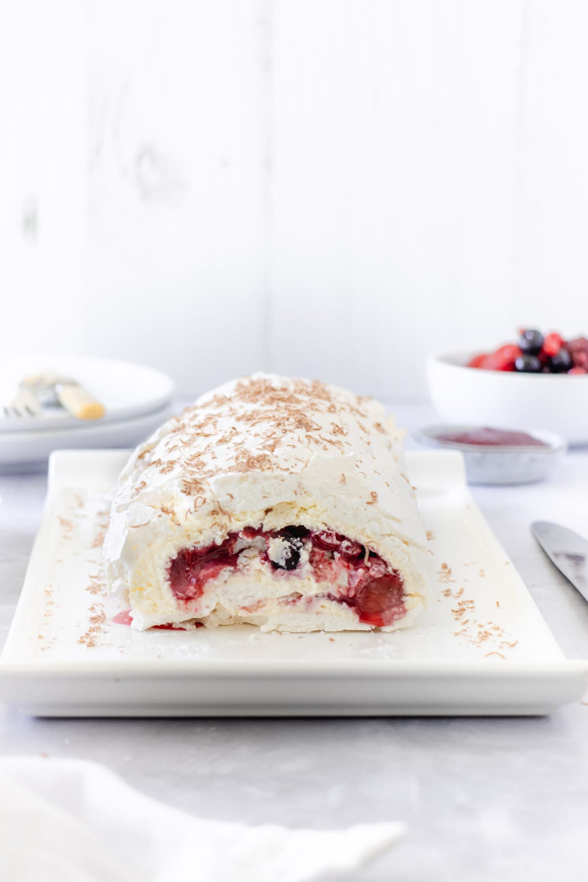 Red berries inside a summer berry meringue roulade with whipped cream