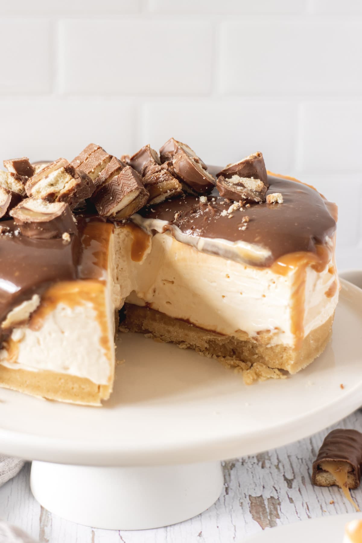 Twix cheesecake with a slice cut out of it