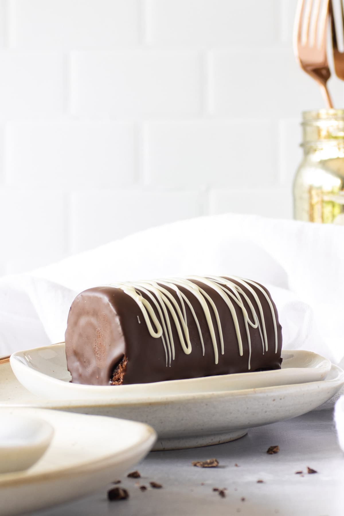 Chocolate coated swissl rolls on a white plate with a white napkin