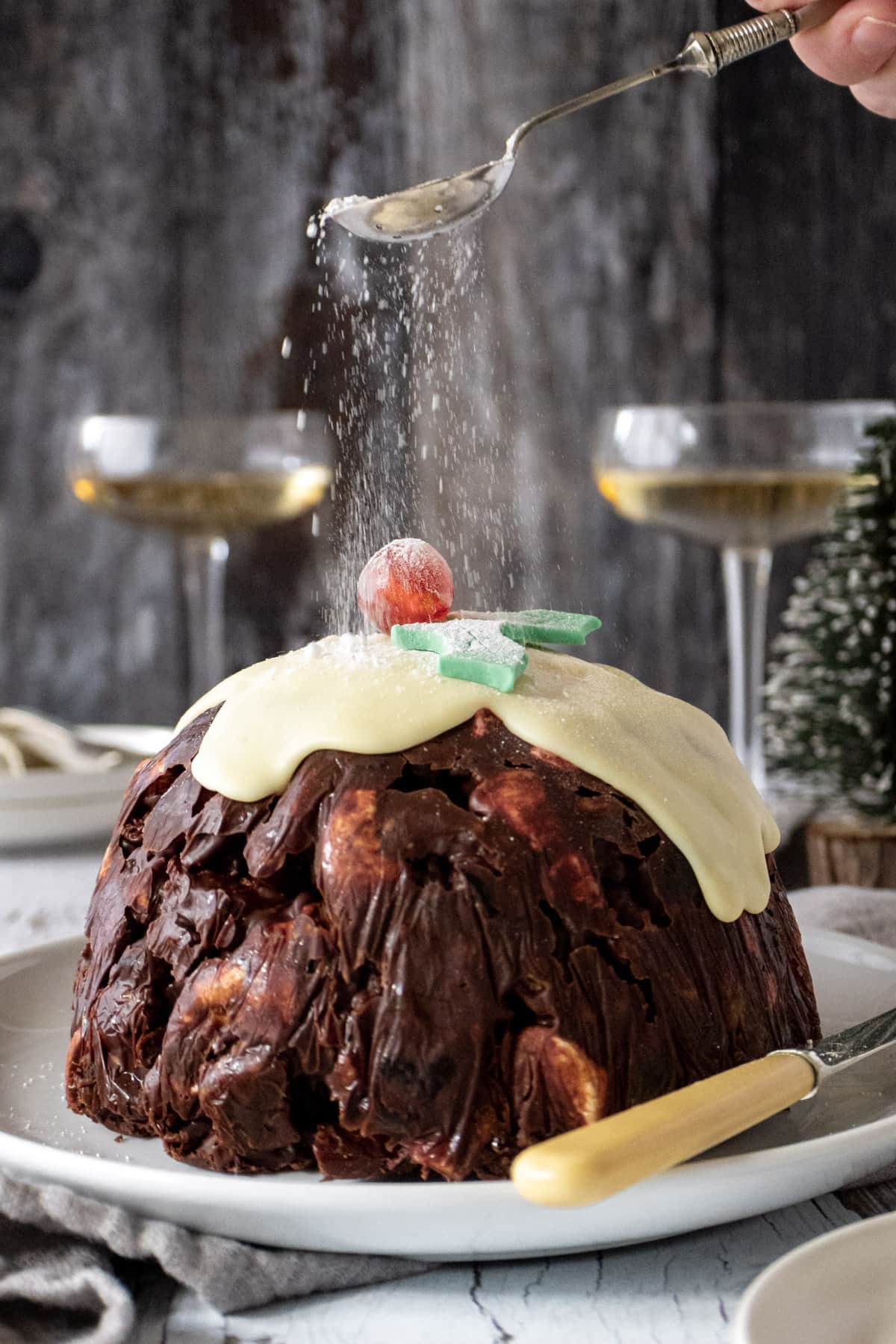 RockIcing sugar being sprinkled over the top of a rocky road Christmas pudding