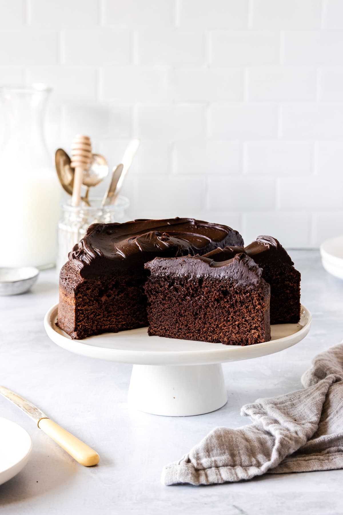 Large chocolate cake covered in chocolate frosting on a white cake stand