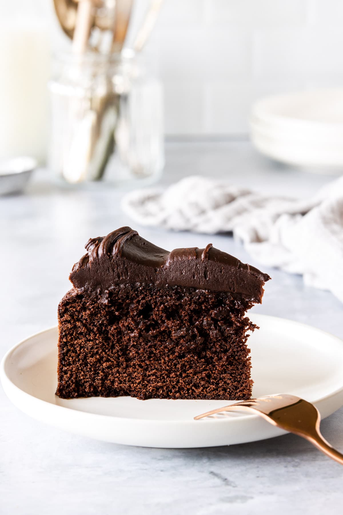 A slice of chocolate cake stood up on a plate
