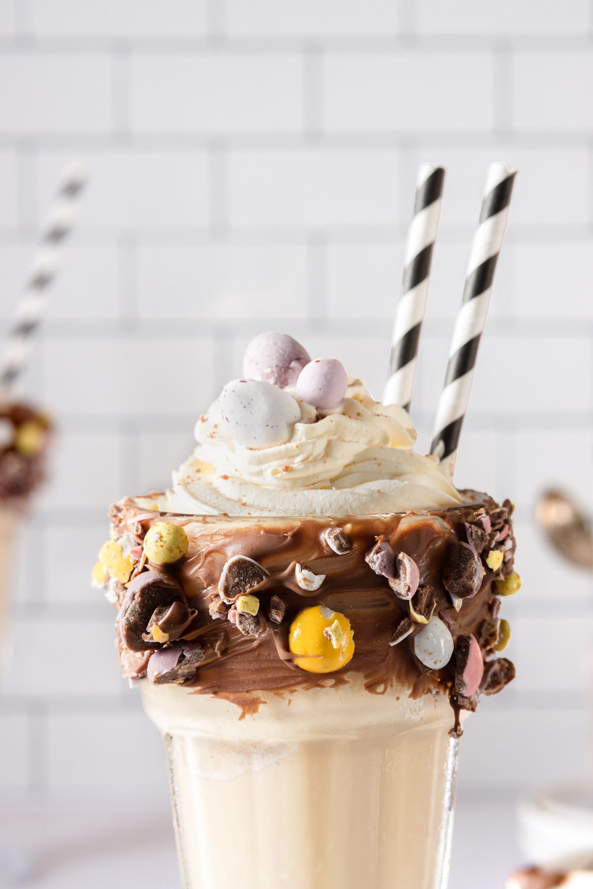 Whipped cream on top of a milkshake glass, coated in chocolate and dipped in crushed chocolate eggs