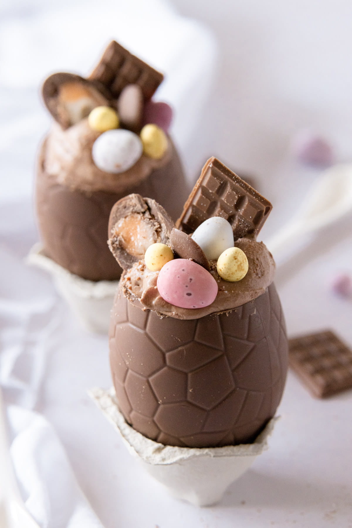 Two chocolate eggs filled with chocolate mousse and topped with Easter chocolate treats