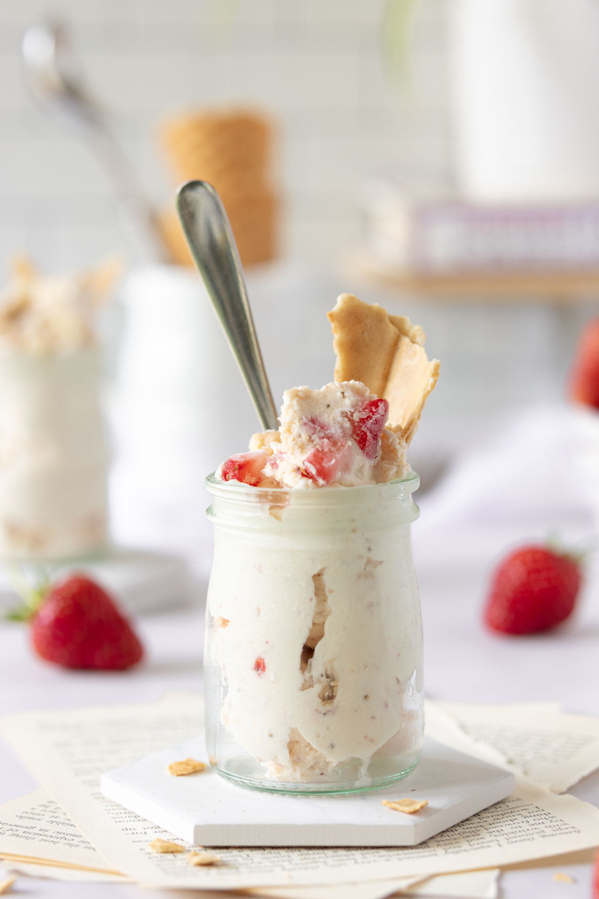 Strawberry Cheesecake Ice Cream in a jar with a piece of waffle in the top and fresh strawberries
