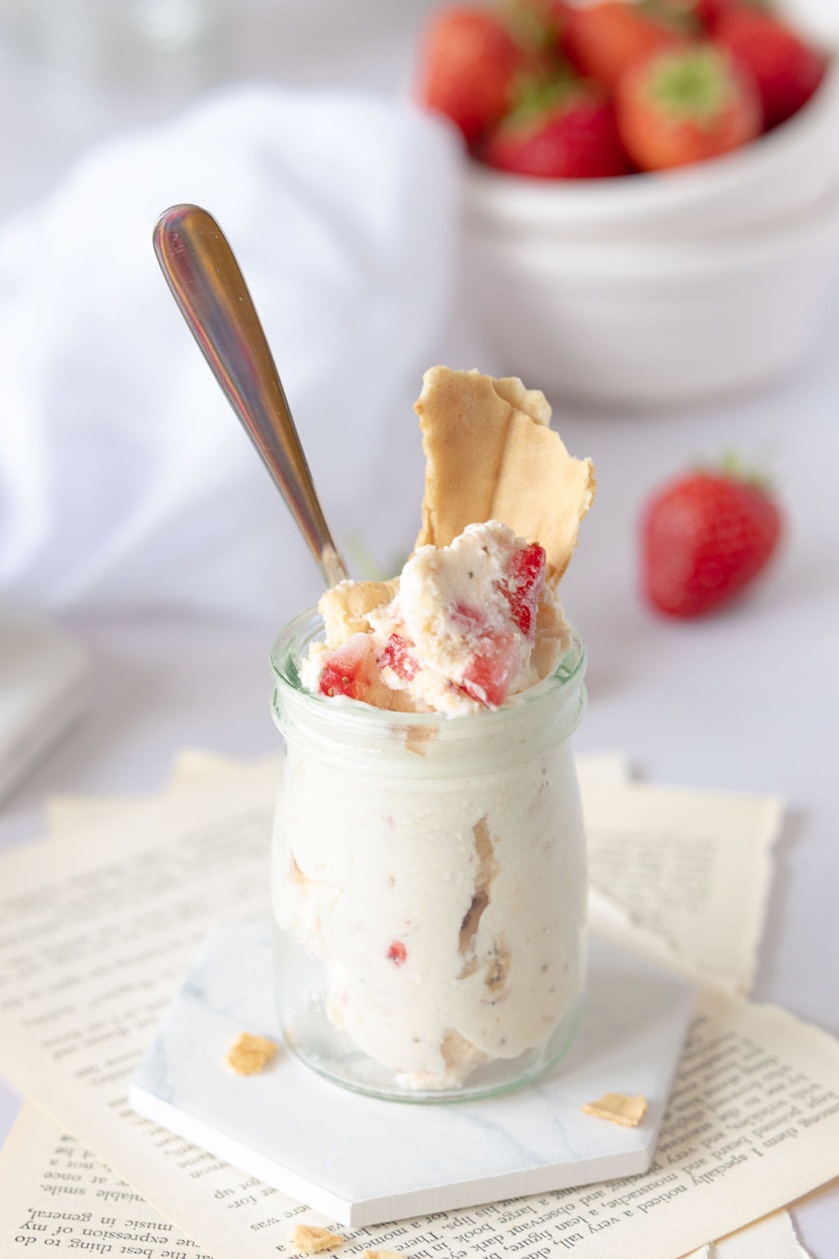 Strawberry Cheesecake Ice Cream in a jar with a piece of waffle in the top and fresh strawberries