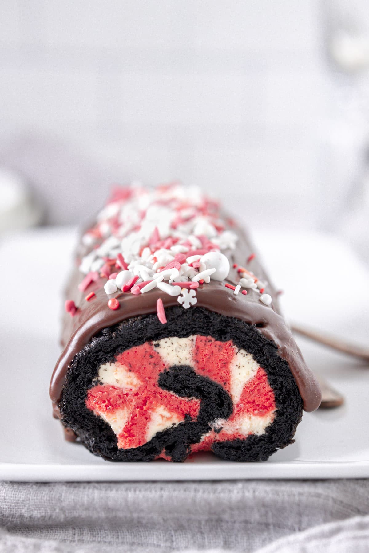 Chocolate Peppermint Swiss Roll filled with red and white cream, on a white plate