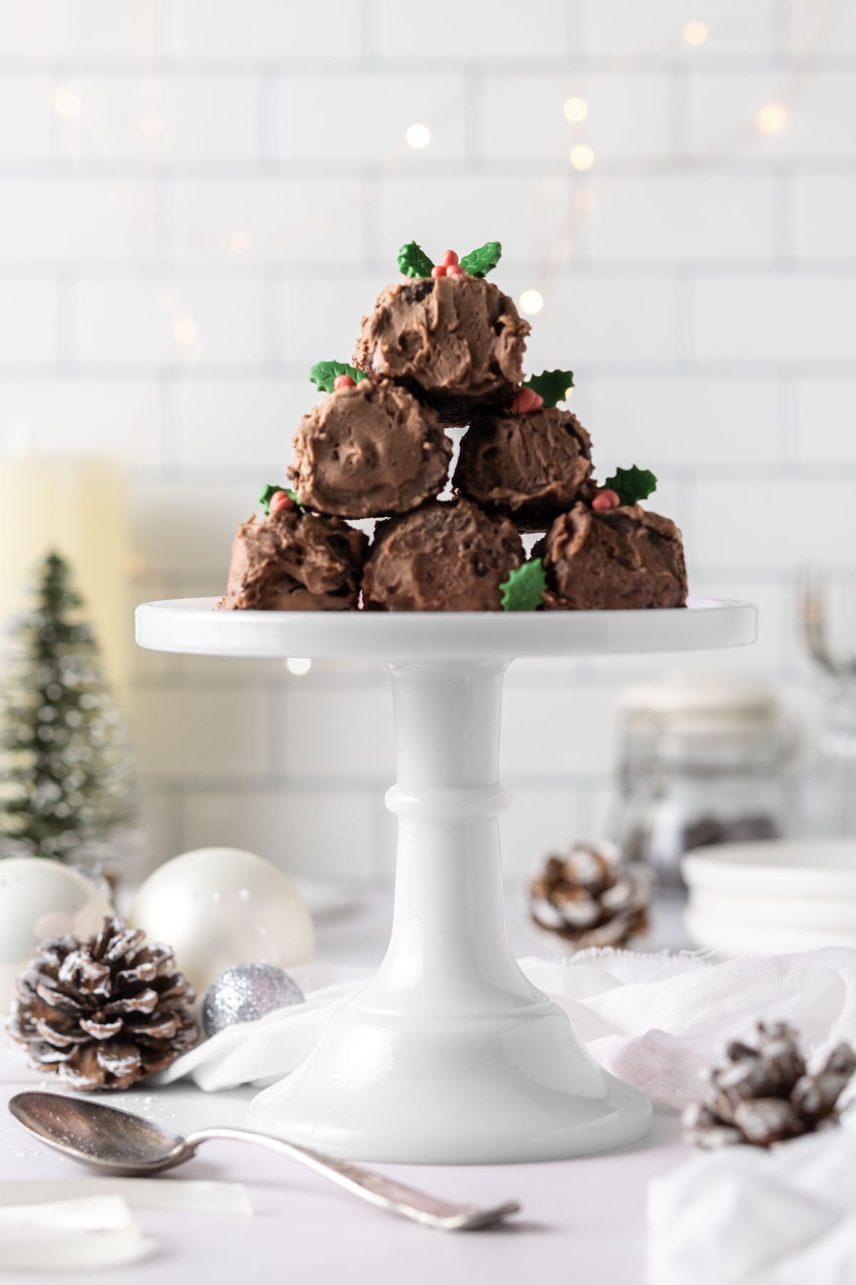 Stack of mini chocolate yule logs on a white cake stand