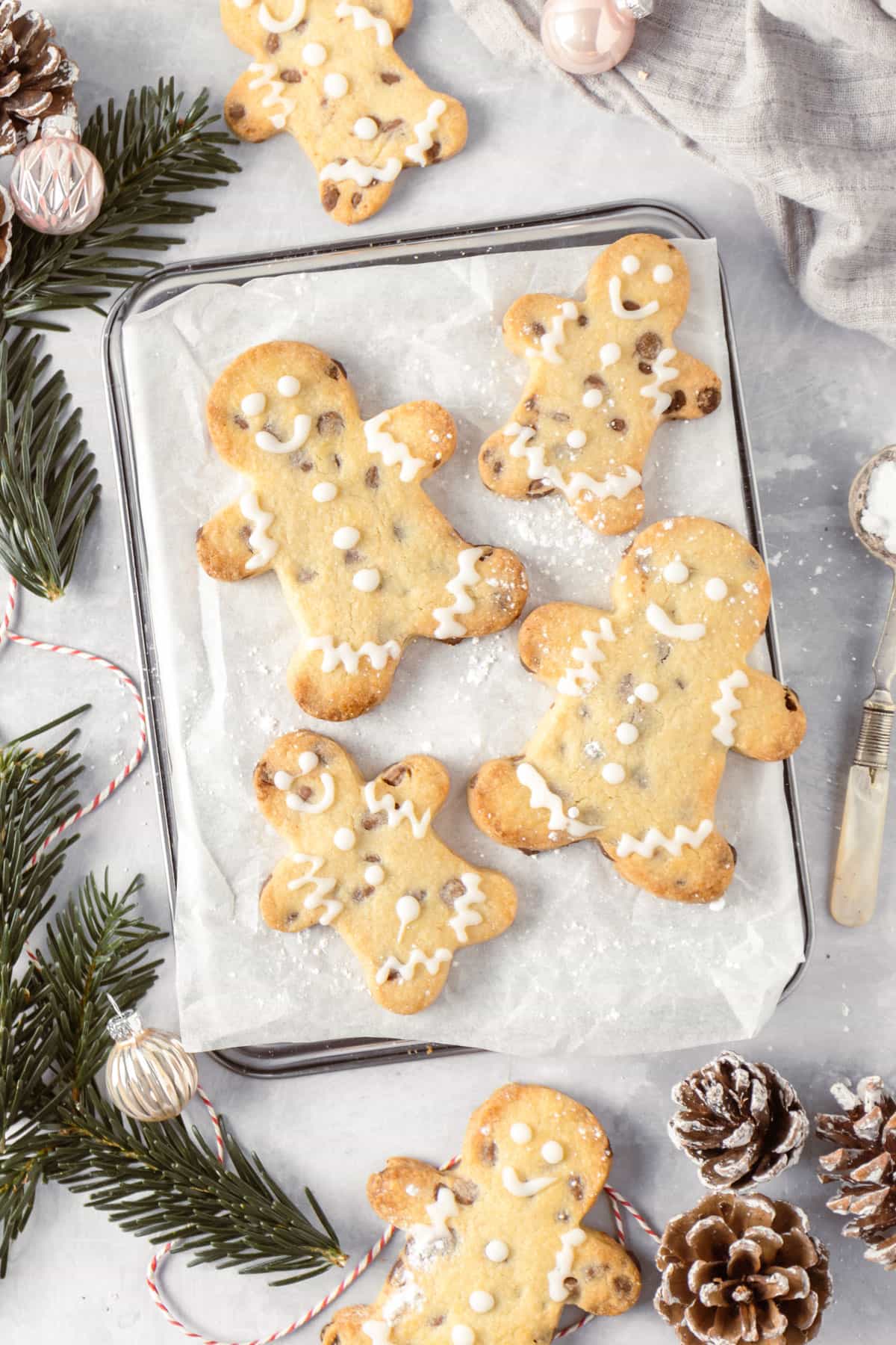 Four shortbread men cookies on a piece of baking parchment, dusted with icing sugar