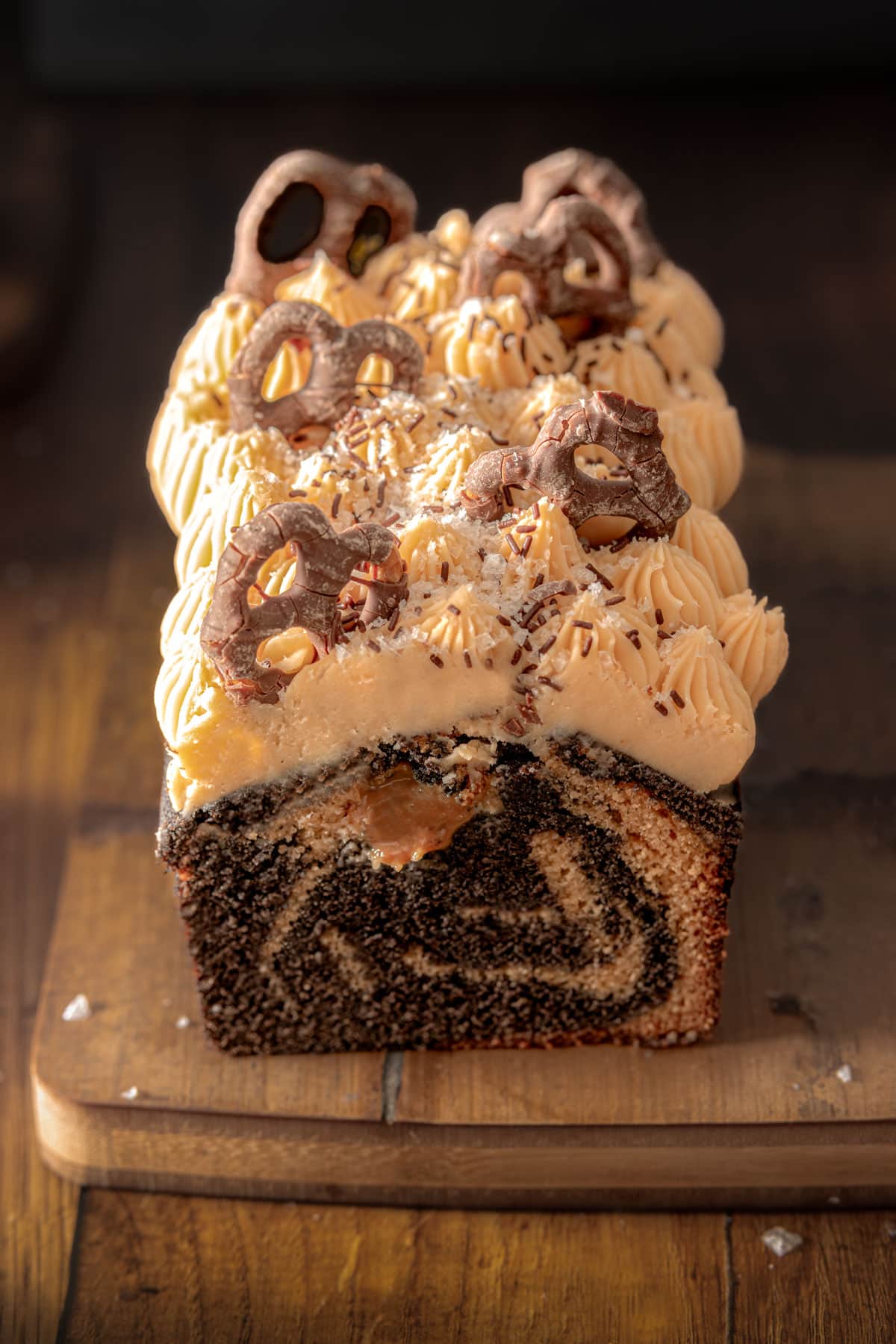 A chocolate caramel loaf cake on a wooden chopping board with the front slice cut off so you can see the marble swirl in the cake batter.